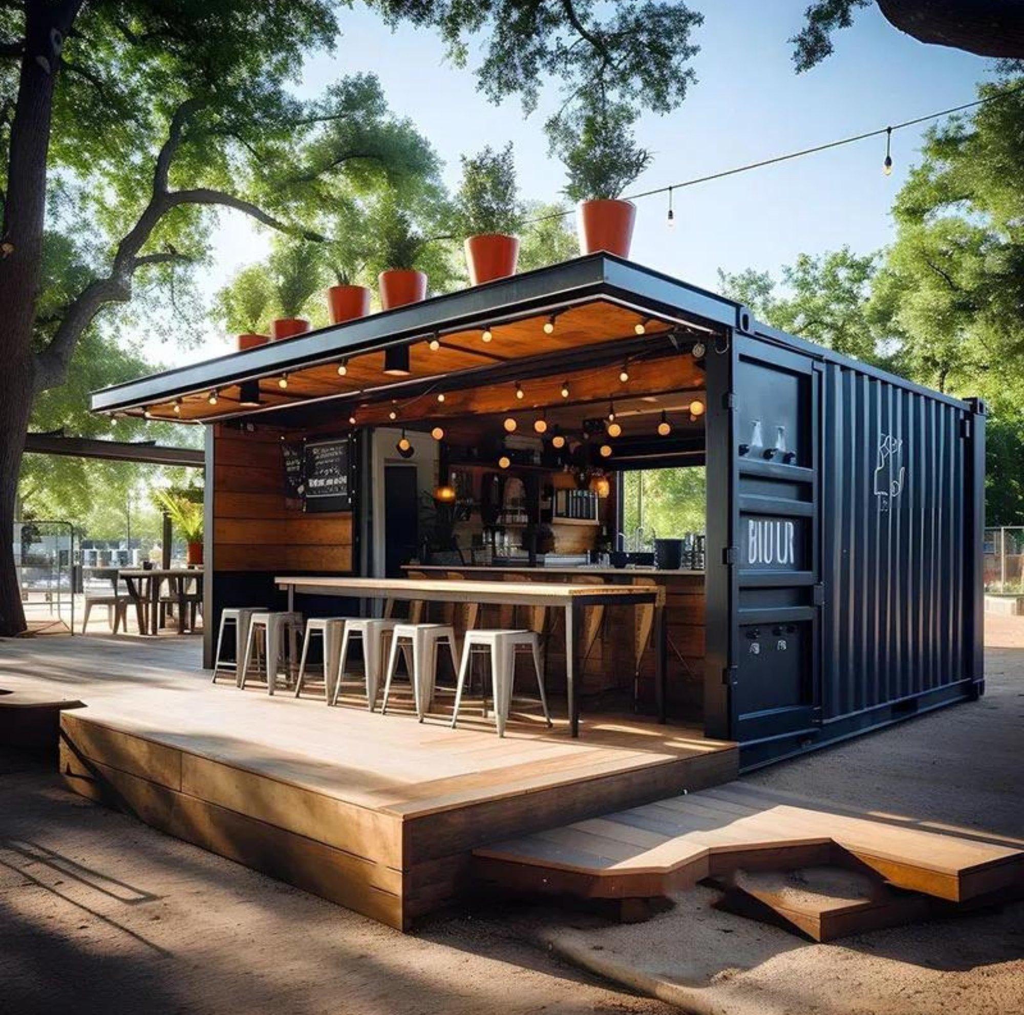 Open-sided container café pavilion with a wood deck, bar stools and string lights under oak trees